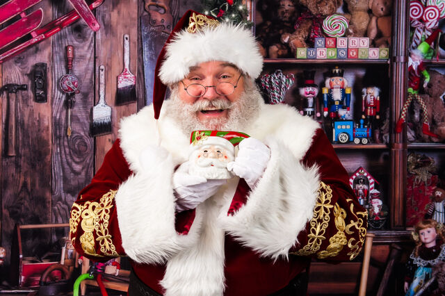 Santa Sarge laughing with a mug of cocoa in his workshop