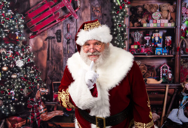 Santa Sarge with a finger to his lips in his workshop