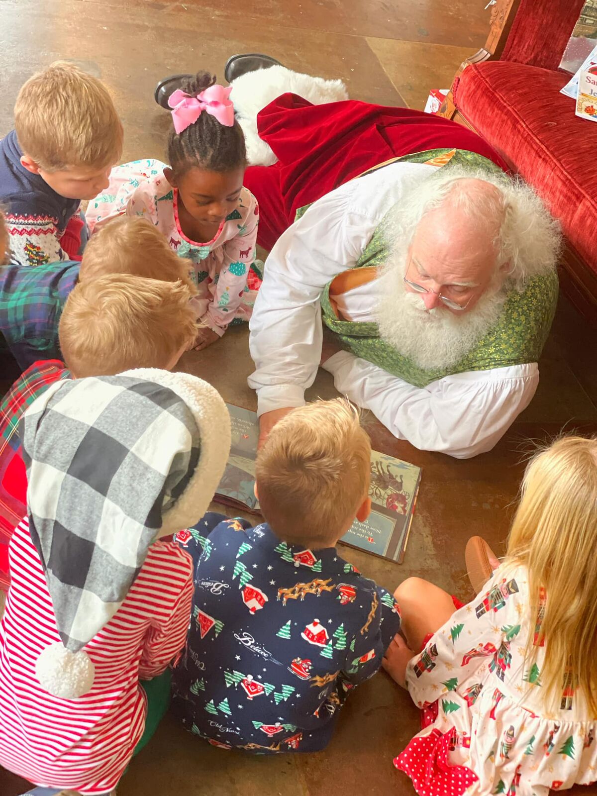 Santa Sarge lying on the floor reading with a group of children