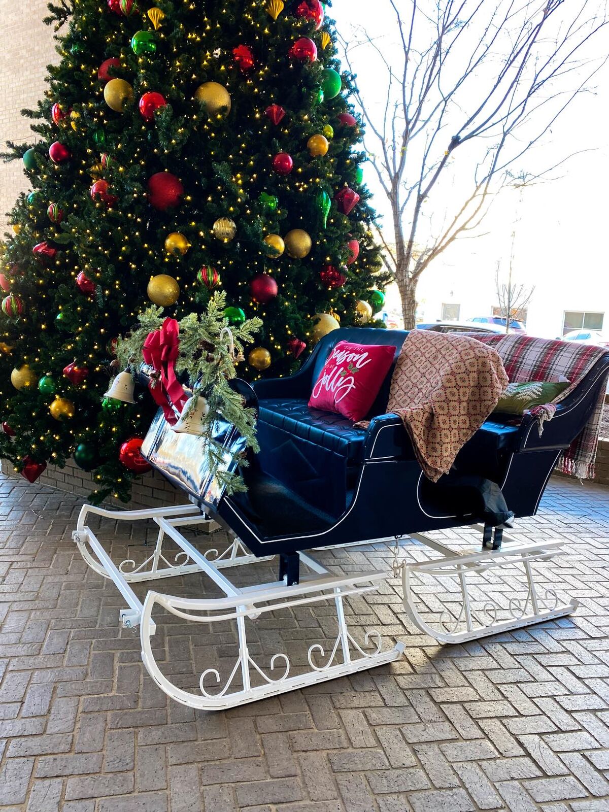 A red sleigh waiting beside a decorated Christmas tree